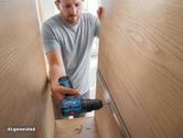 Một người đàn ông mặc đồ bảo hộ đang khoan vào khung tủ gỗ.
