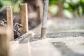 Máy rung bê tông làm phẳng bề mặt bê tông mới đổ trong khung gỗ.