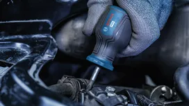 Người đàn ông đeo thiết bị bảo hộ đang dùng tua vít để sửa chữa một chi tiết kim loại.