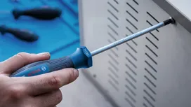 Một người dùng tua vít để siết chặt ốc vít trên một tấm kim loại.