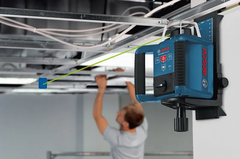 Dụng cụ cân bằng bằng laser chiếu một đường màu xanh lá cây khi một người đang lắp đặt trần treo.