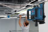 Dụng cụ cân bằng bằng laser chiếu một đường màu xanh lá cây khi một người đang lắp đặt trần treo.